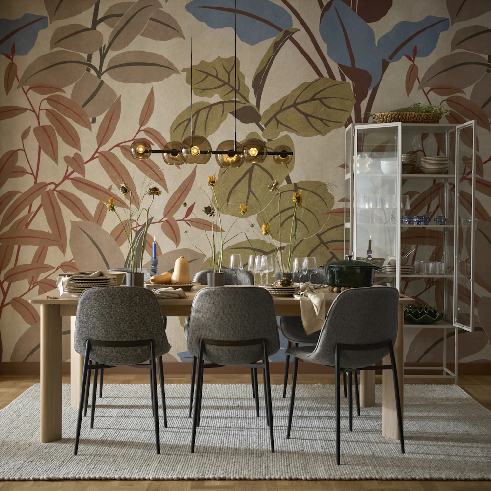 En matgrupp med sex gråa stolar står i ett rum med stormönstrad tapet.