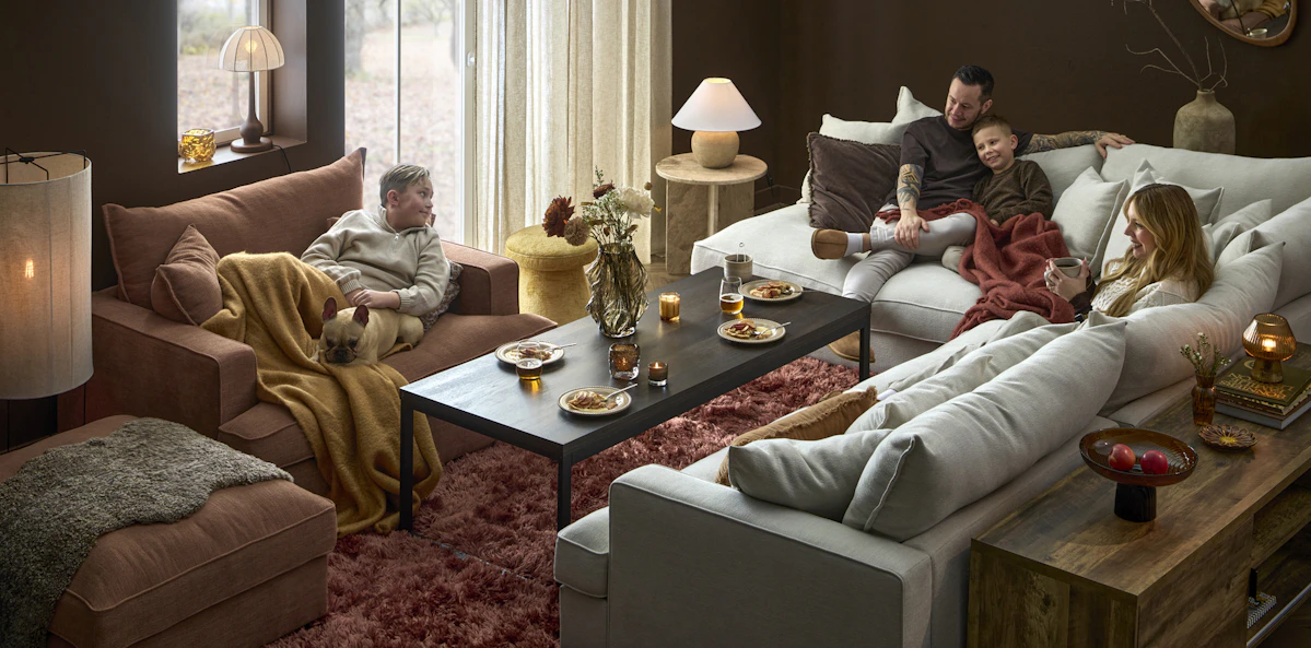 I en stor, djup Rossi soffa sitter en familj med två barn och en hund och myser