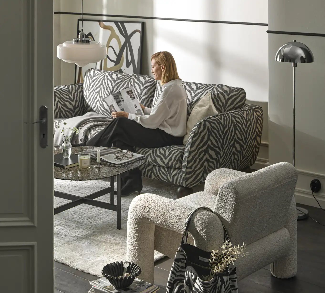 I ett stilrent vardagsrum sitter en kvinna i en zebramönstrad Madison-soffa