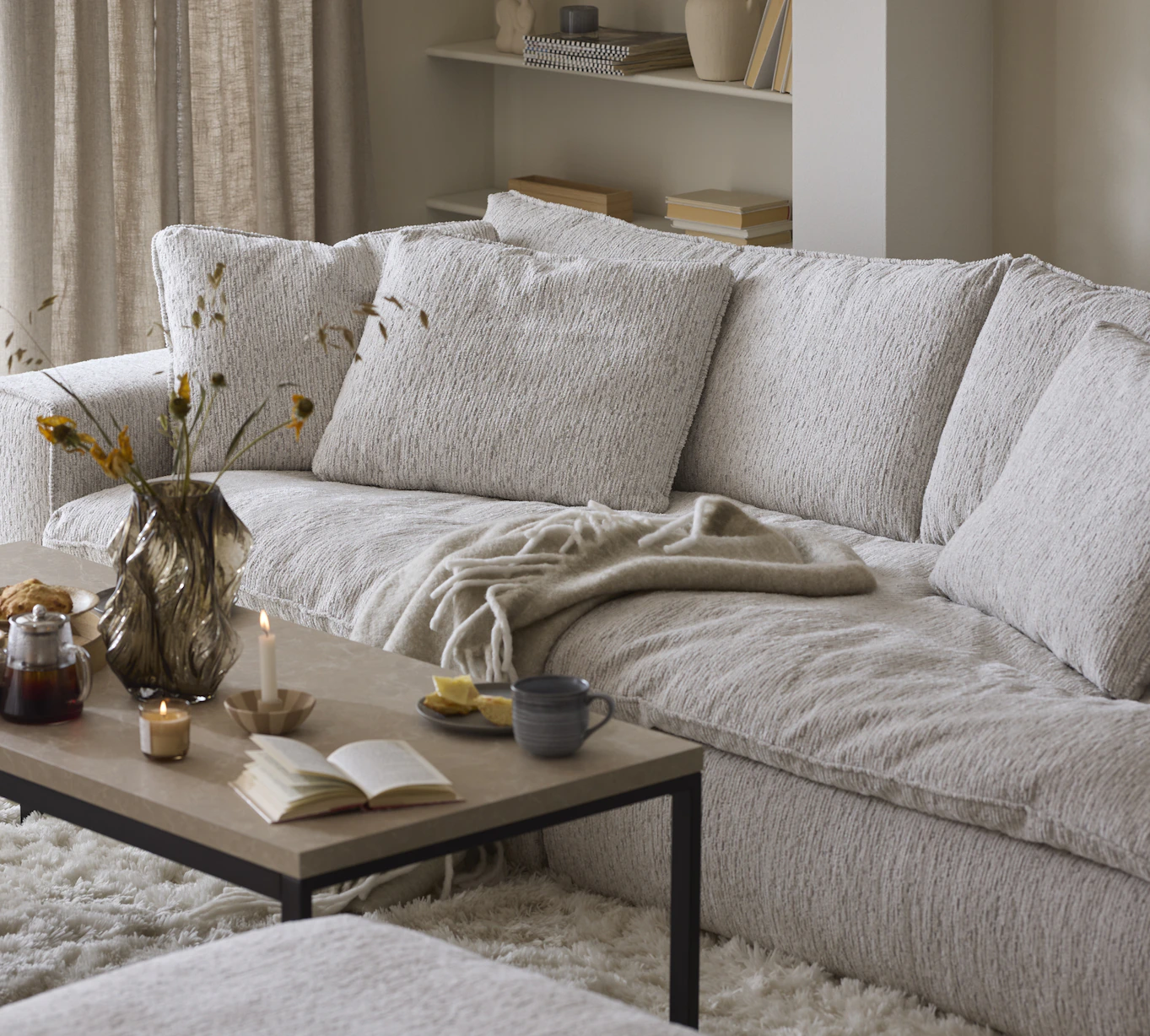 En ljus, djup soffa står i ett beige vardagsrum bakom ett soffbord i trä