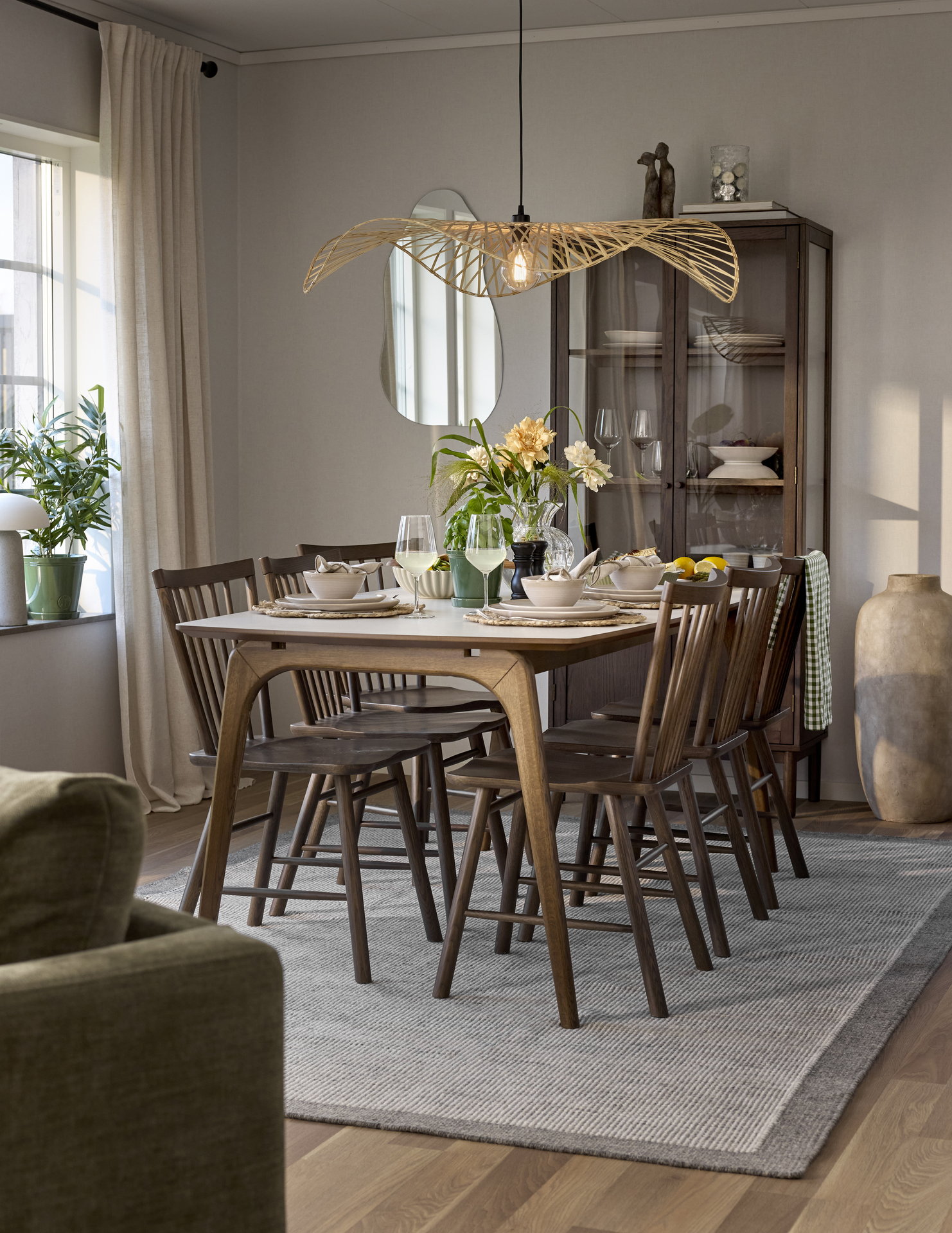 En matgrupp i mörkt trä med ljus bordsskiva står framför ett vitrinskåp.