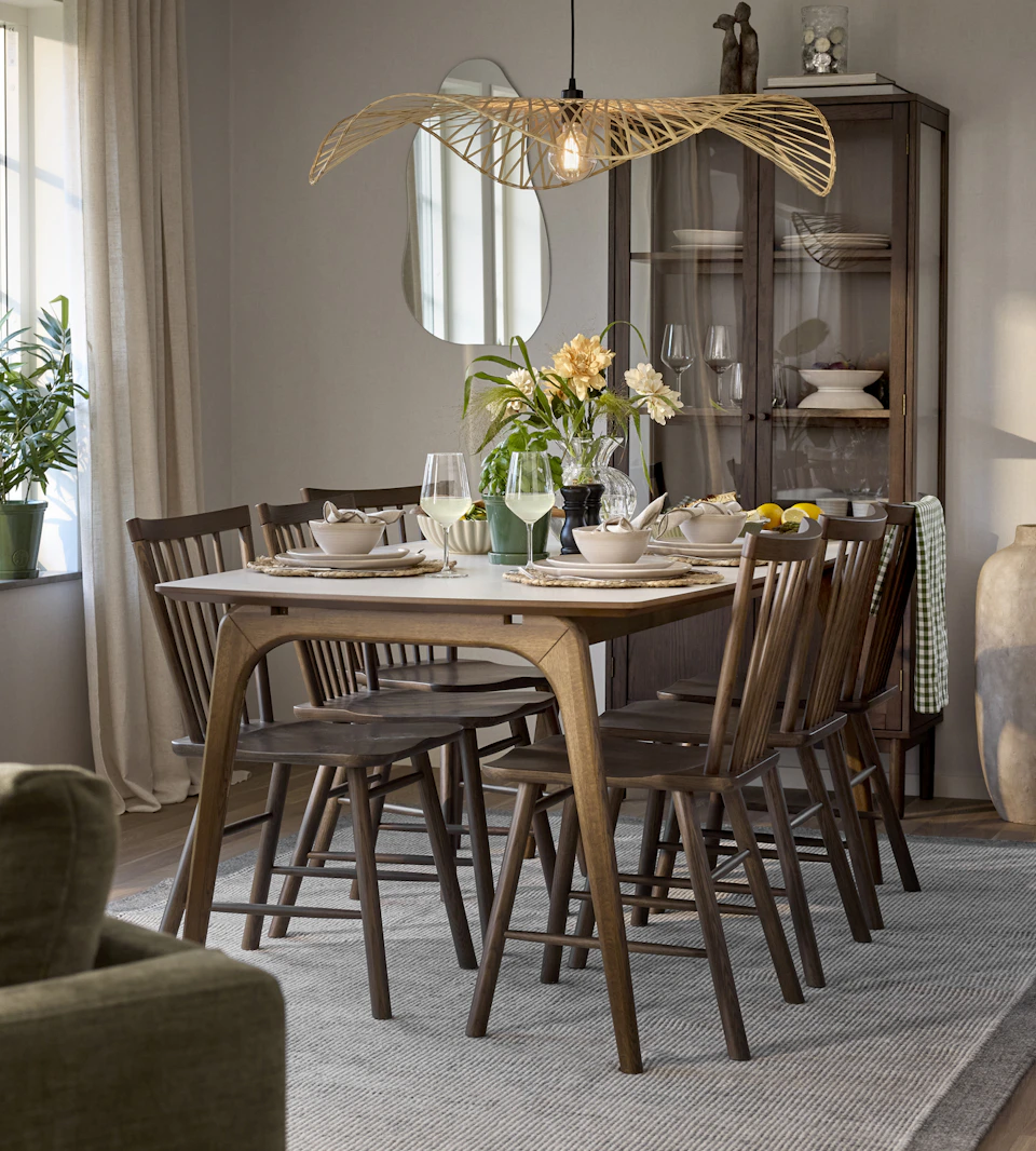 En matgrupp i mörkt trä med ljus bordsskiva står framför ett vitrinskåp.