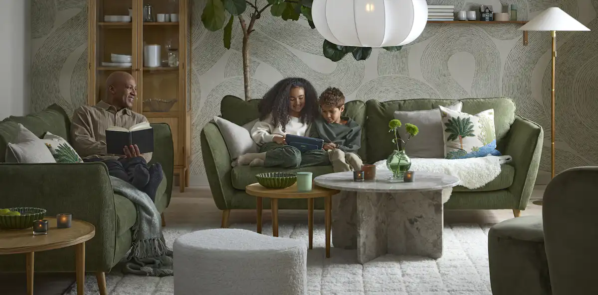 I ett vardagsrum i gröna toner sitter två barn och läser i en grön Madison soffa