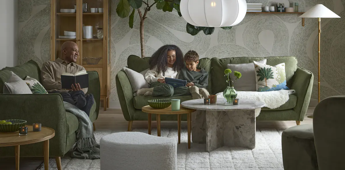 I ett vardagsrum i gröna toner sitter två barn och läser i en grön Madison soffa