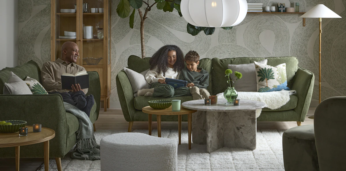 I ett vardagsrum i gröna toner sitter två barn och läser i en grön Madison soffa