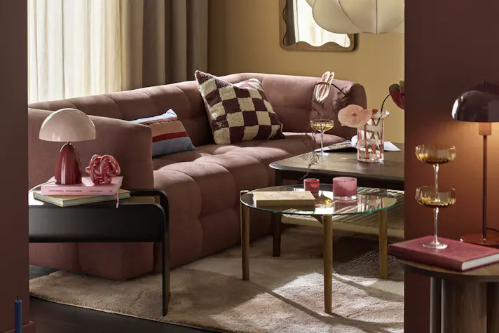 I ett gult vardagsrum står en rostfärgad soffa i modern design