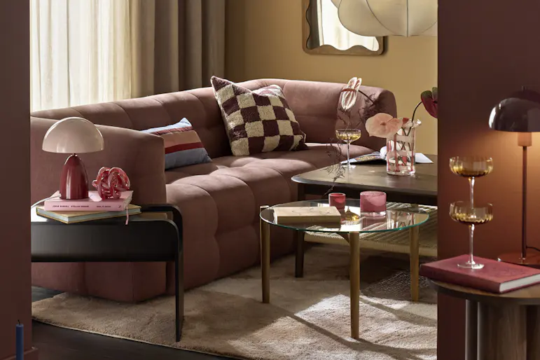 I ett gult vardagsrum står en rostfärgad soffa i modern design