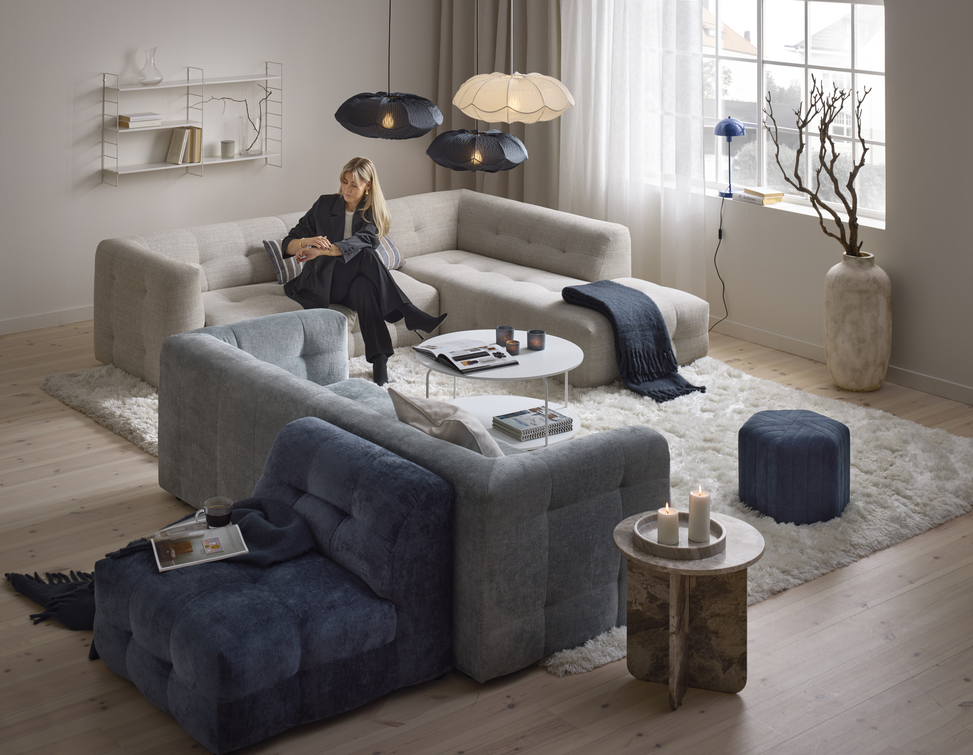 En kvinna sitter i en beige soffa i ett rum som går i beige och blåa toner