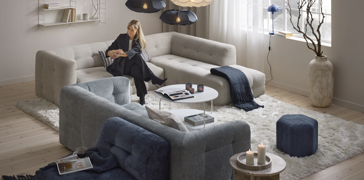 En kvinna sitter i en beige soffa i ett rum som går i beige och blåa toner