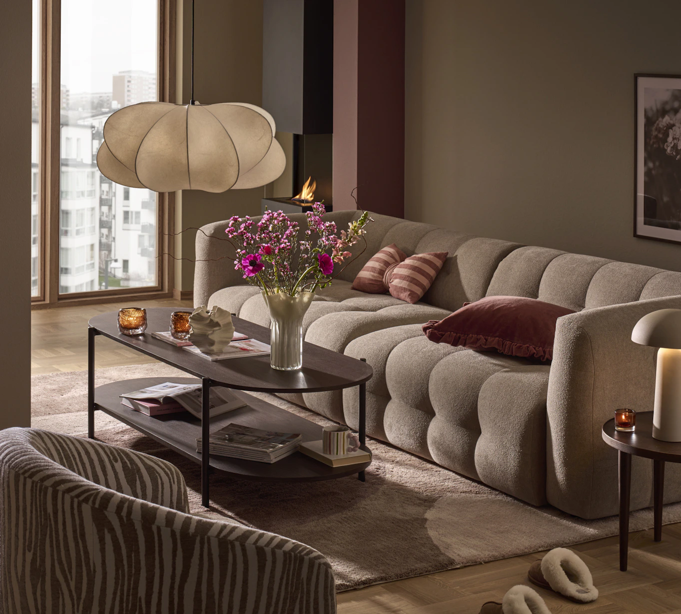 I ett beigemålat vardagsrum med rosa detaljer står den trendsäkra soffan Bella