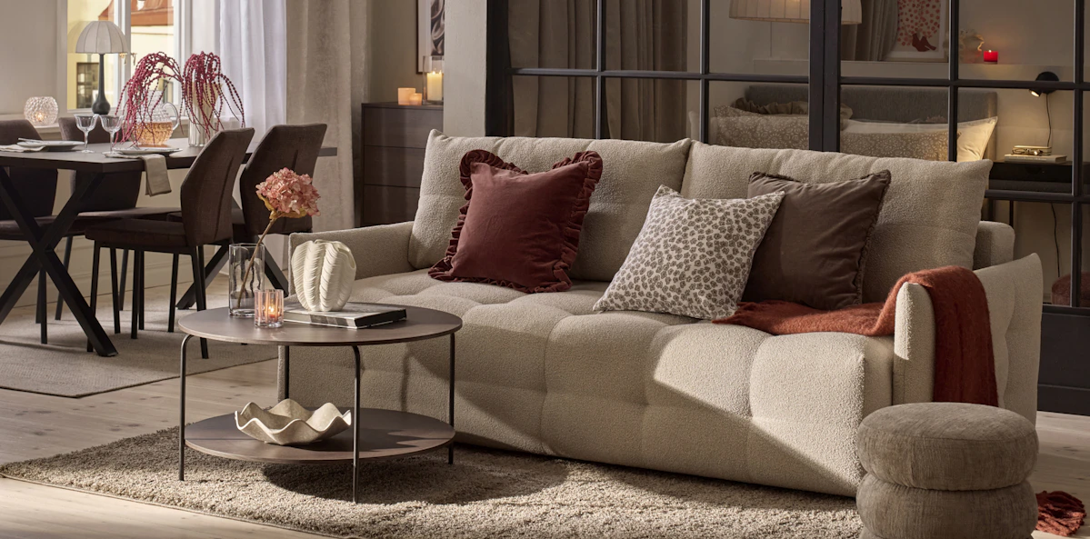 En beige bella bäddsoffa står i ett vardagsrum som går i beige, brunt och vinrött