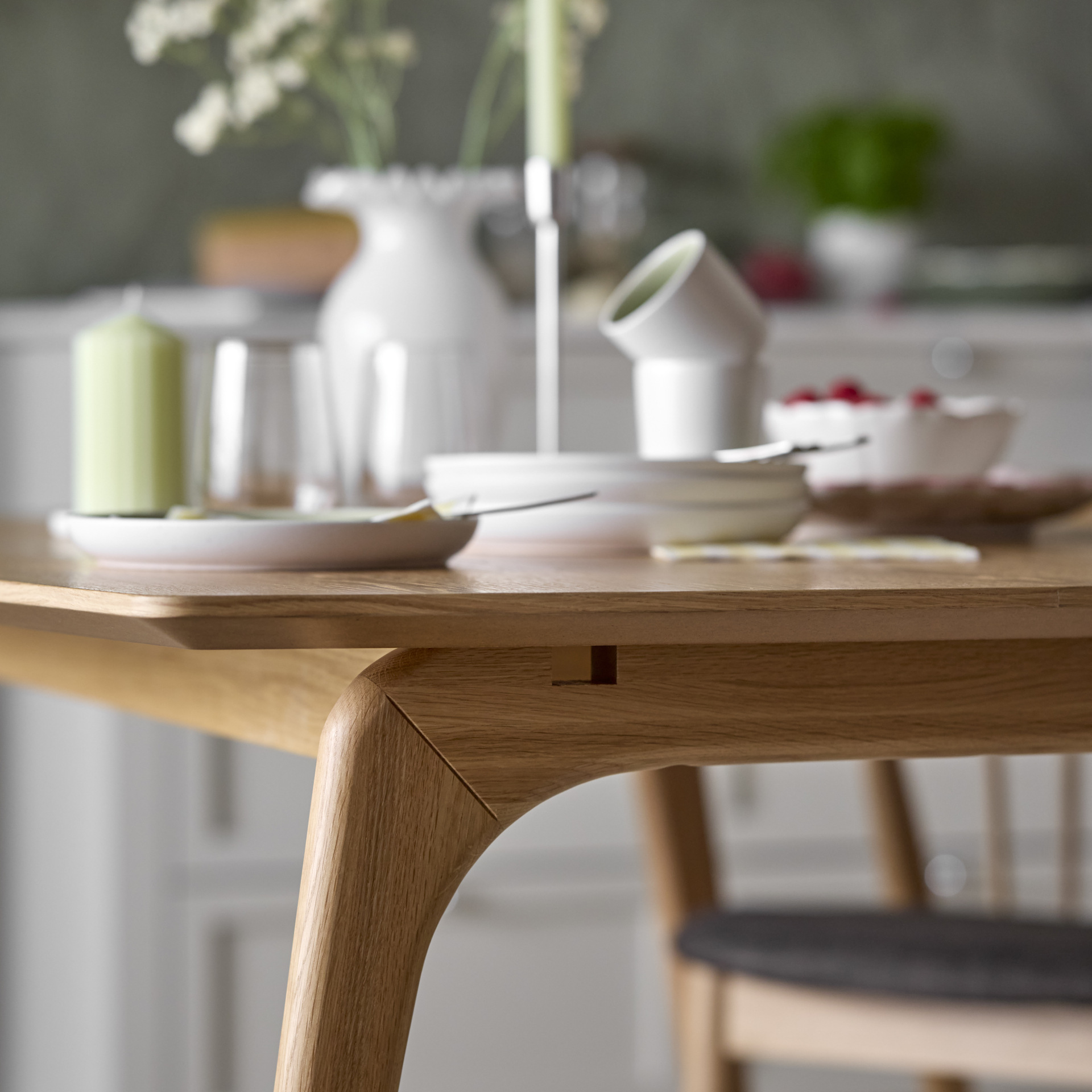 Detaljbild på den rundade kanten av ett matbord i trä.