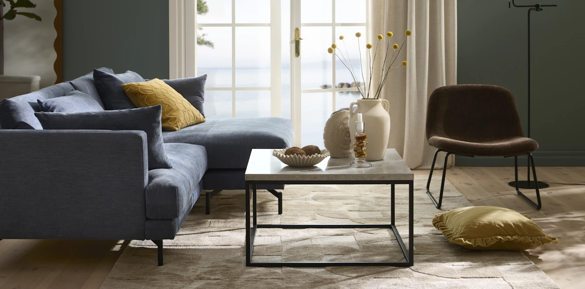 I ett stilrent vardagsrum står en blå soffa med raka former