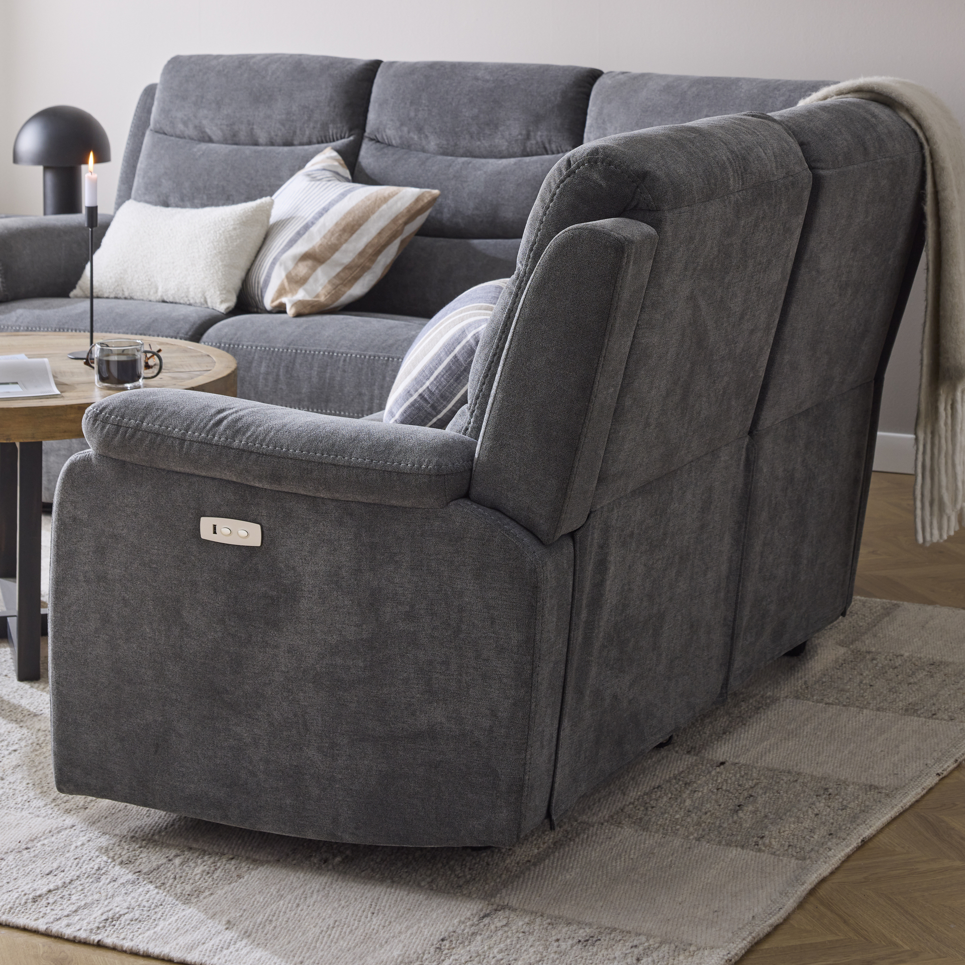 Sidan av en hörnsoffa som har reclinerfunktion med knappar vid armstödet