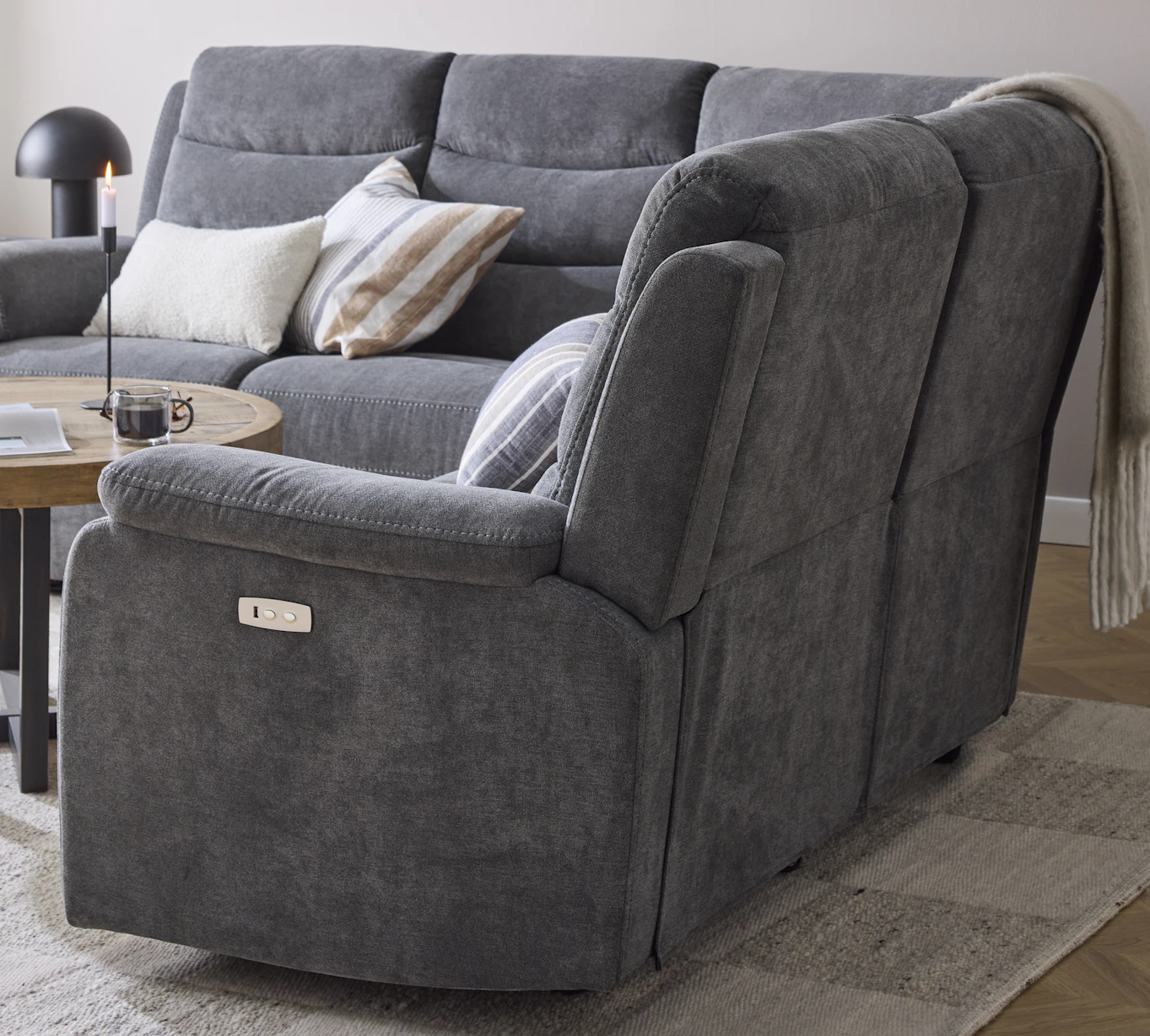 Sidan av en hörnsoffa som har reclinerfunktion med knappar vid armstödet