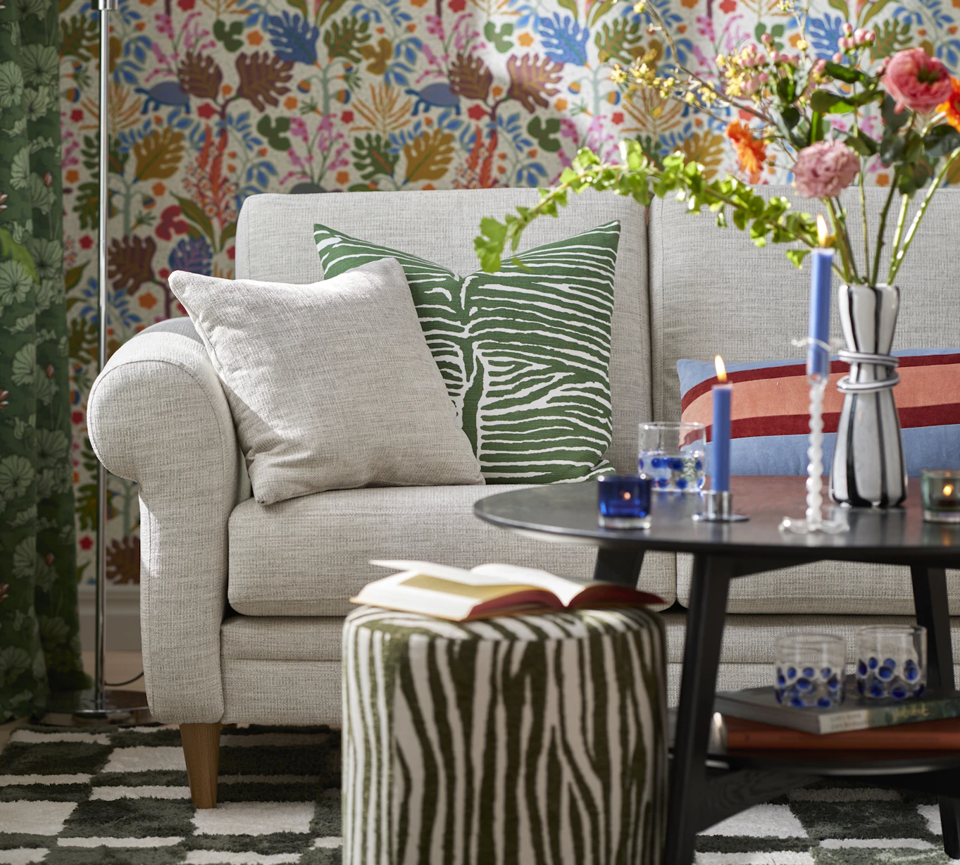 I ett kulört vardagsrum står en ljusgrå soffa