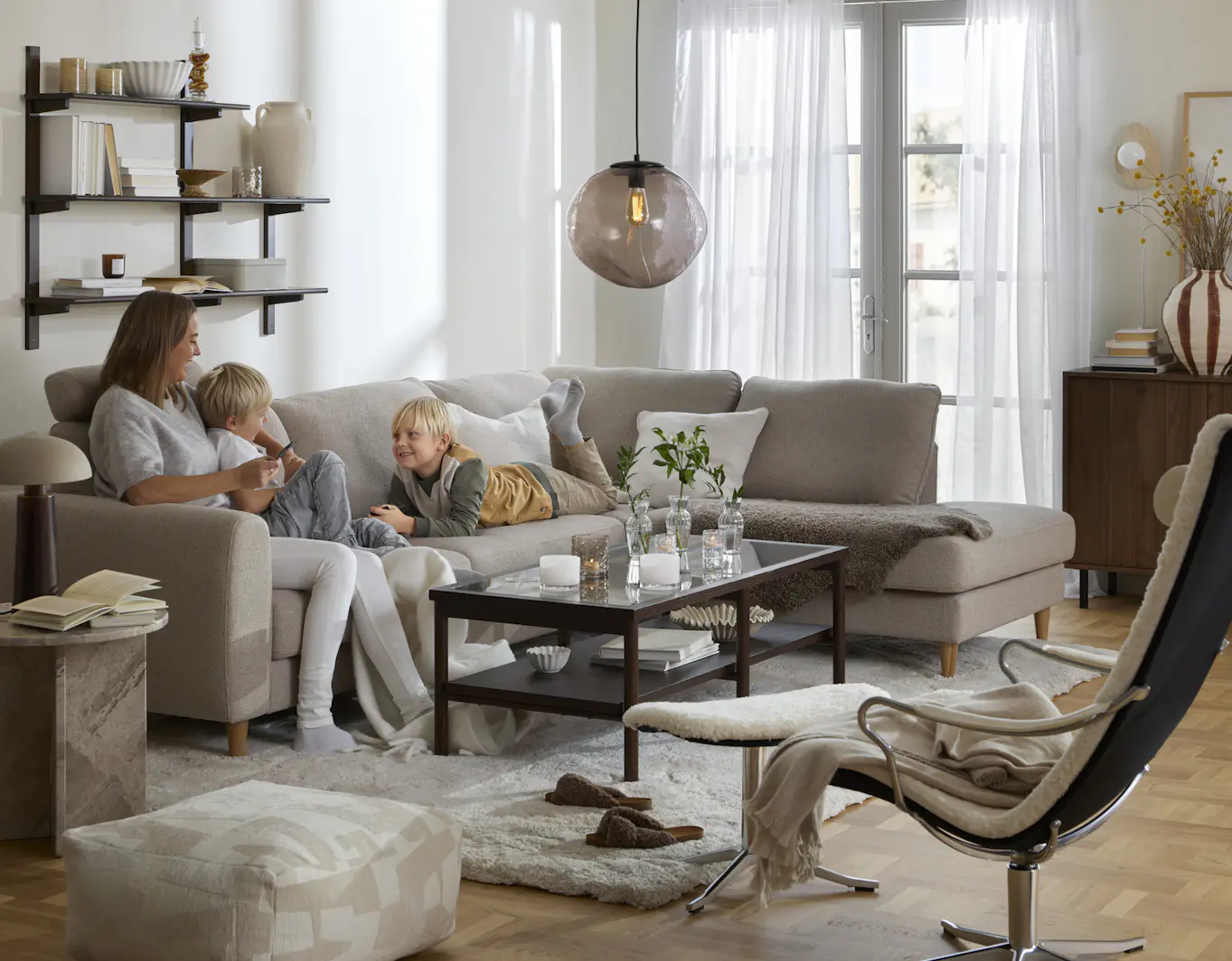I en beige divansoffa sitter en kvinna och två barn
