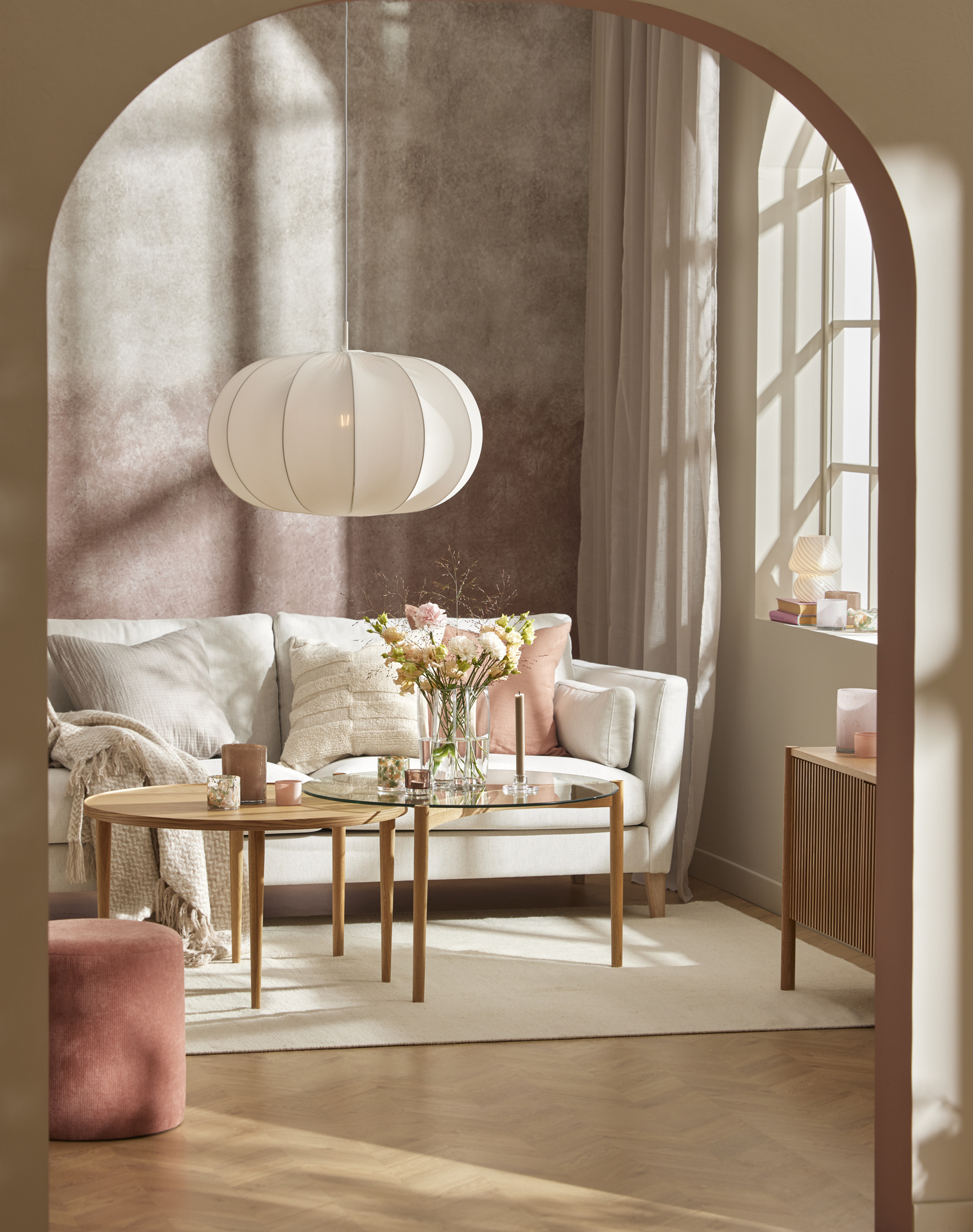 Bakom ett satsbord i ljust trä står en vit soffa