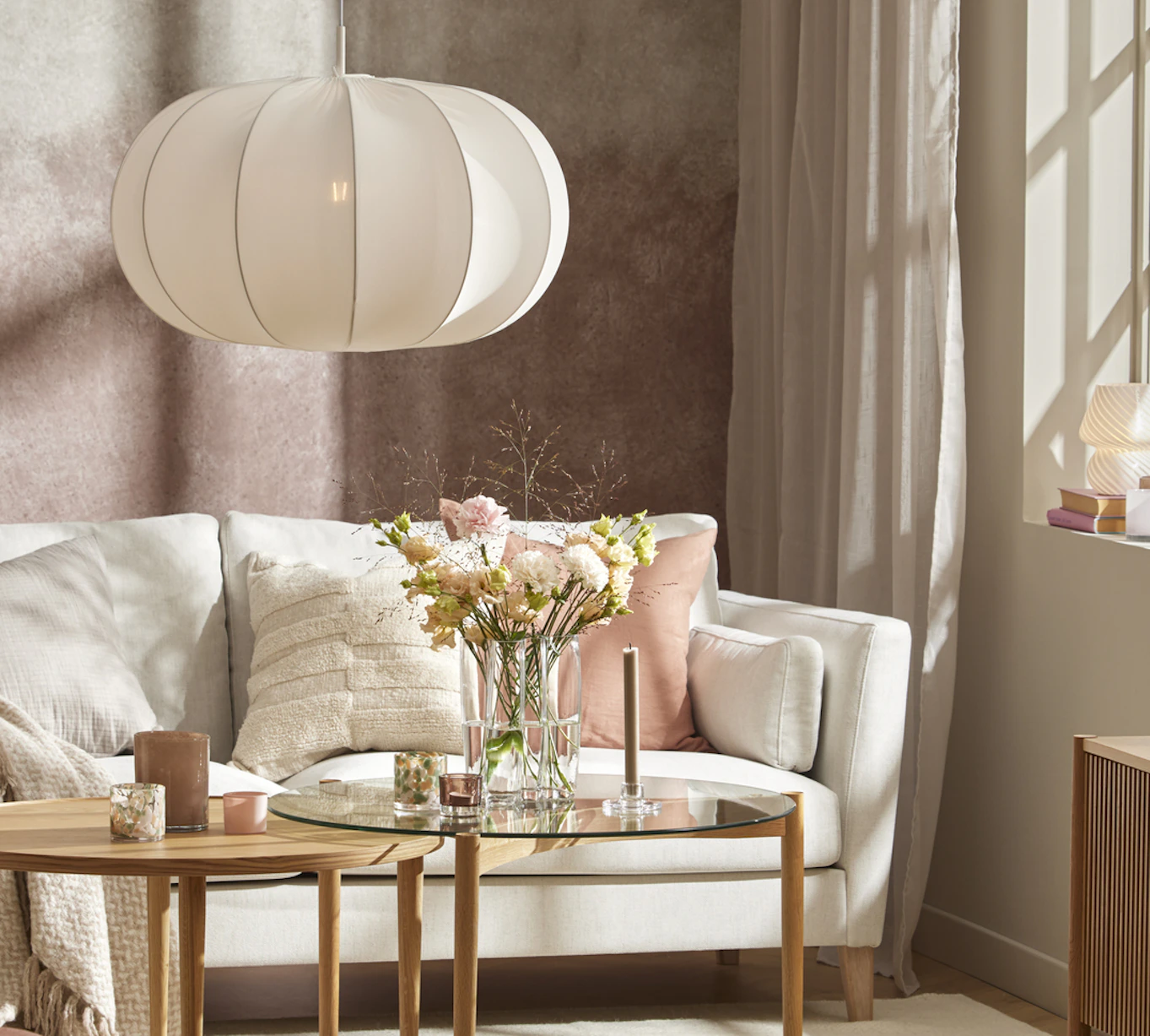 Bakom ett satsbord i ljust trä står en vit soffa