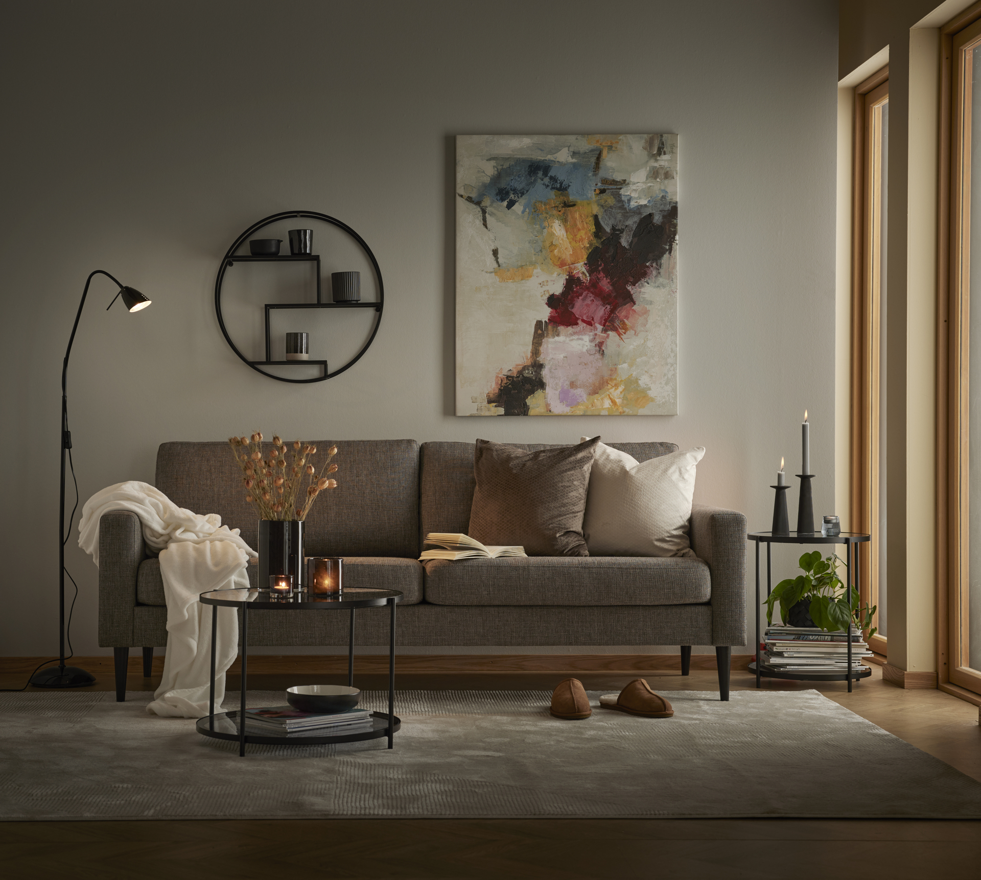 En grå soffa står i ett vardagsru bakom ett soffbord i glas och metall