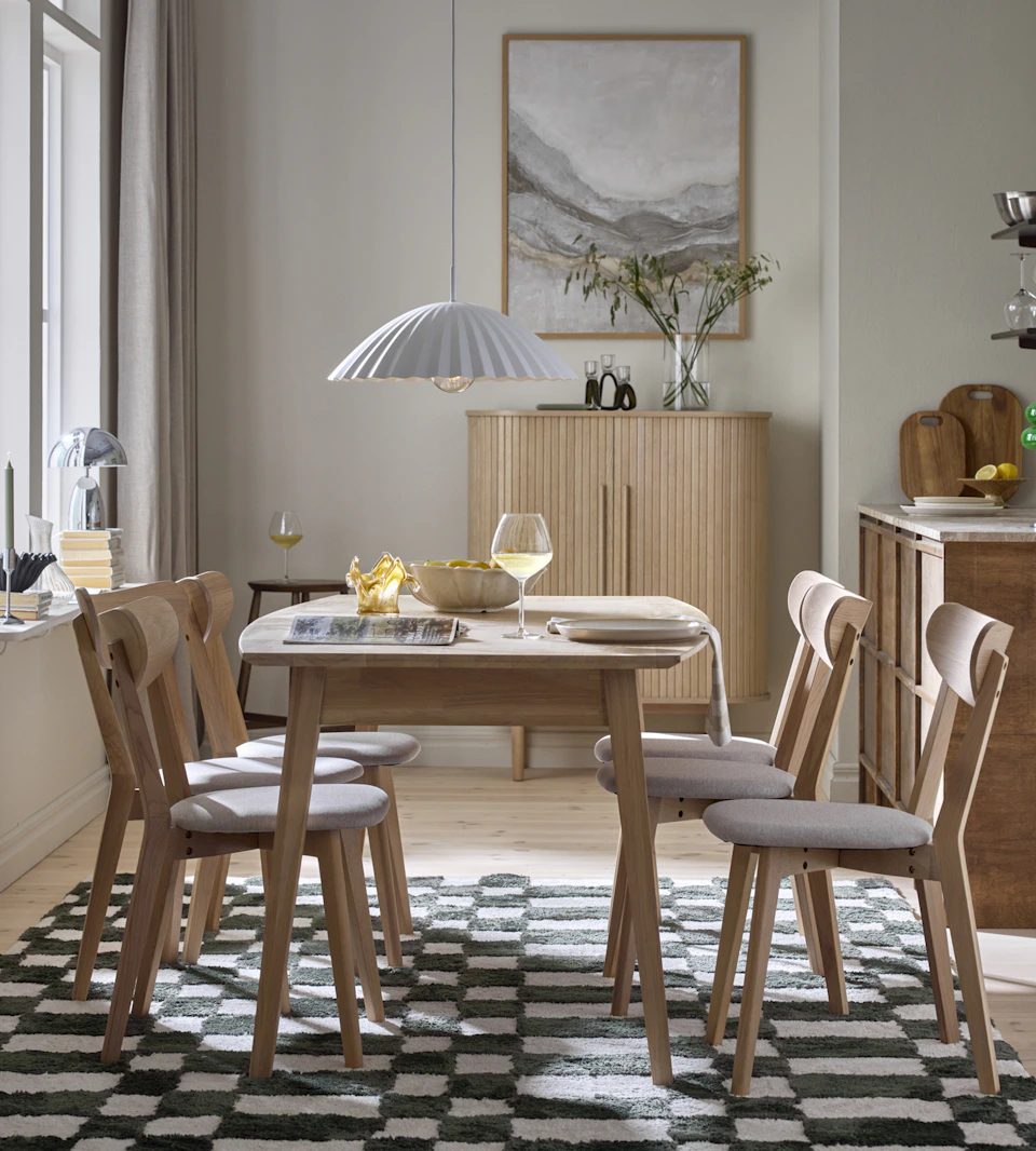 En matgrupp i ljust trä står på en grön- och vitmönstrad matta i ett ljust rum.