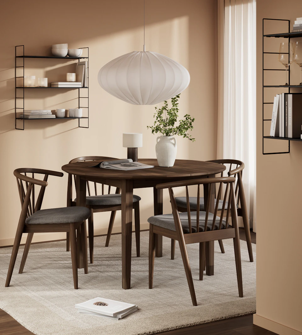 En rund matgrupp i mörkt trä står i ett ljust matrum.