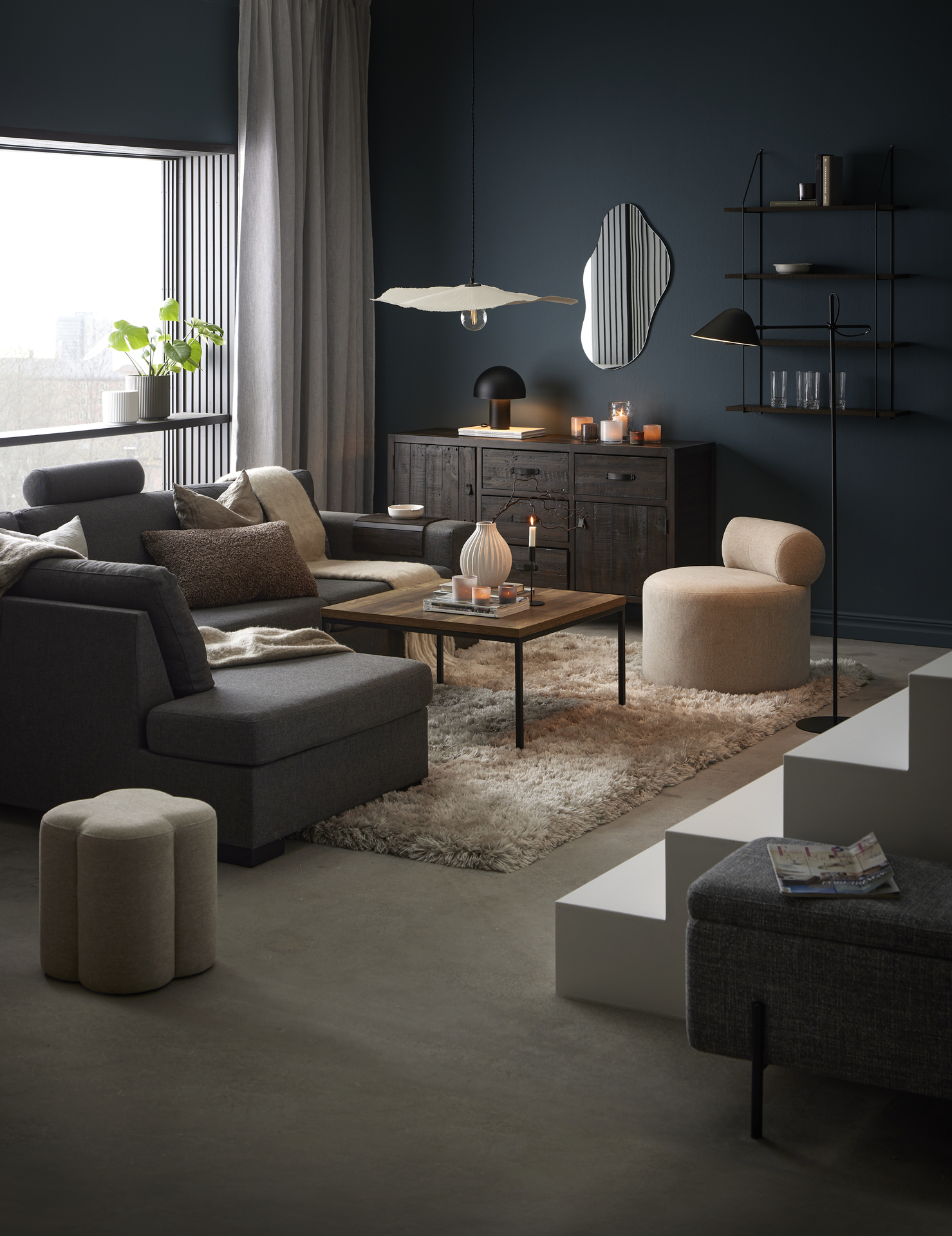 I ett mörkt och murrigt vardagsrum står en mörkgrå divansoffa