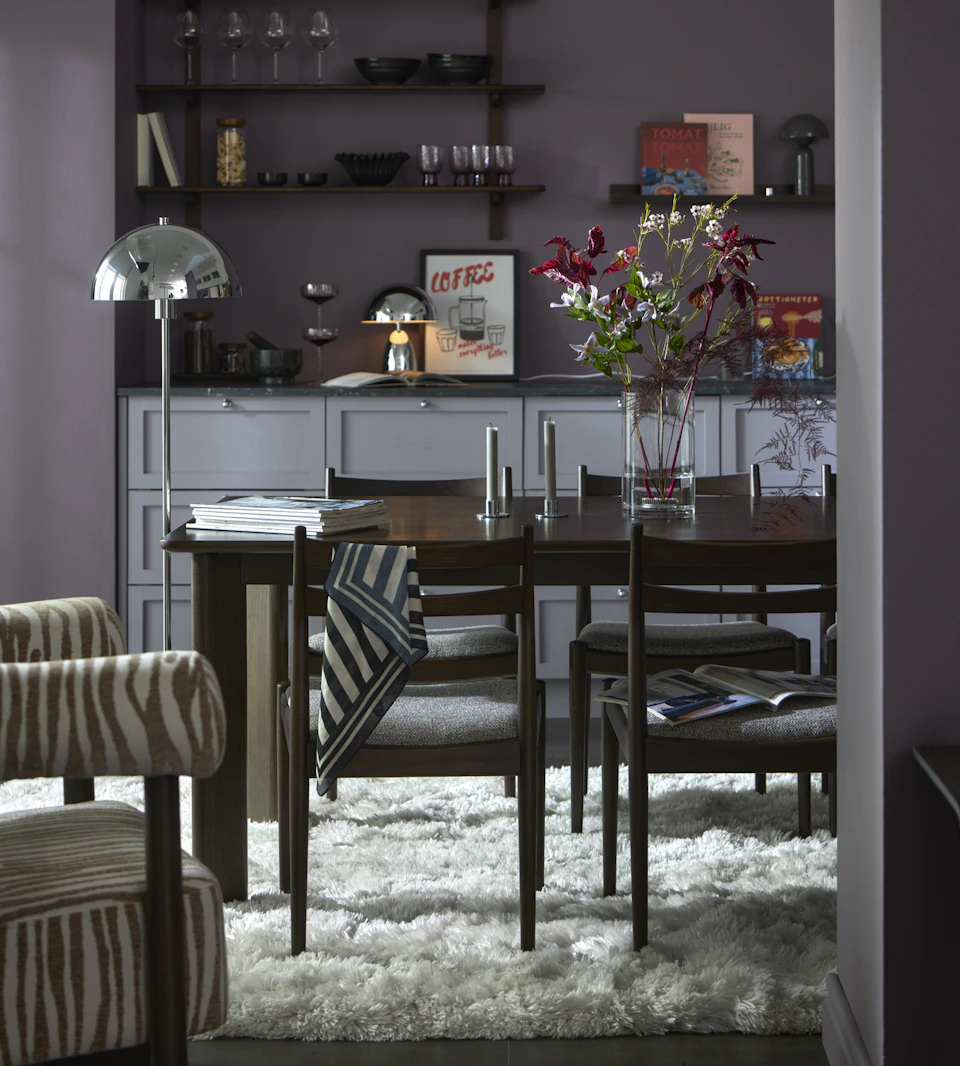 En matgrupp i mörkt trä står i ett grått kök med mörkt grålila väggar.