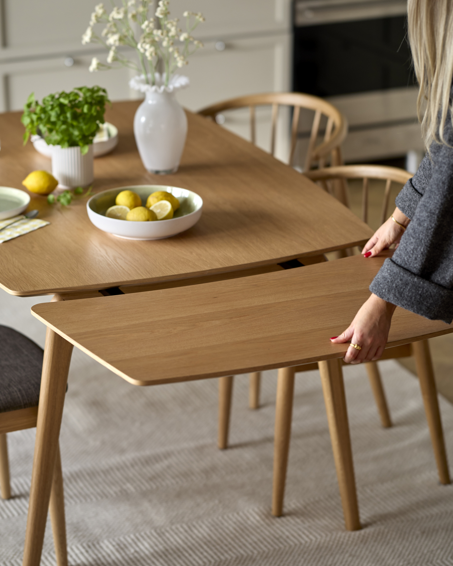 En person sätter fast en tilläggsskiva på ett matbord i trä.