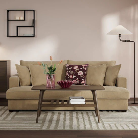 beige tvåsittssoffa står i vardagsrum med ljusa väggar.