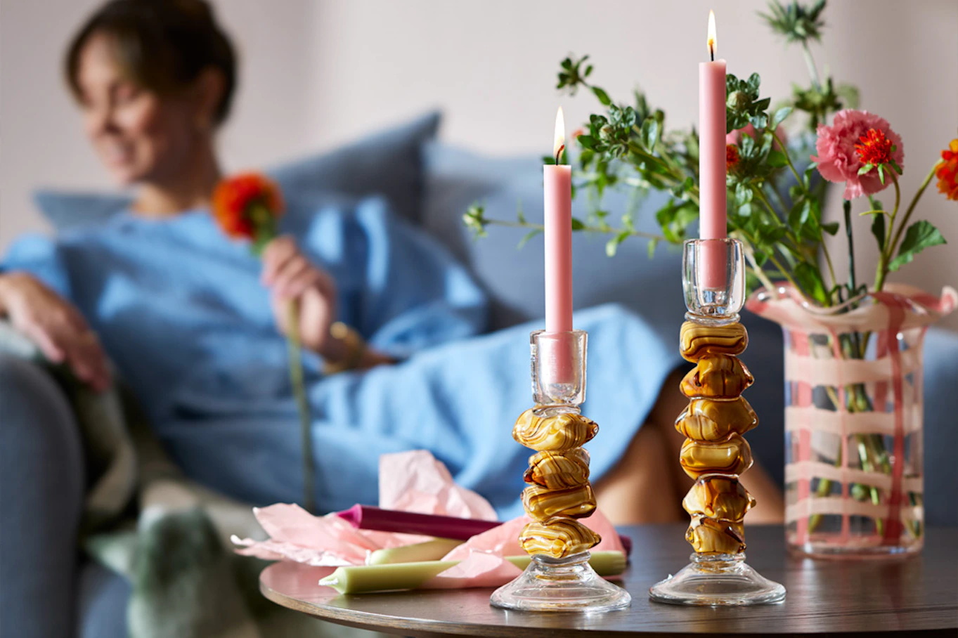 Två Svanenmärkta stearinljus brinner, ståendes i moderna ljusstakar på soffbord.