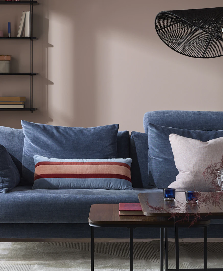 en blå soffa står i ett vardagsrum med rosa väggar