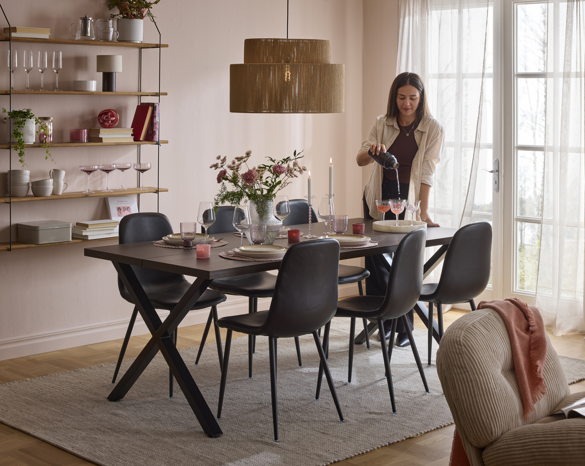 tjej häller upp dryck i glas vid ett matbord 