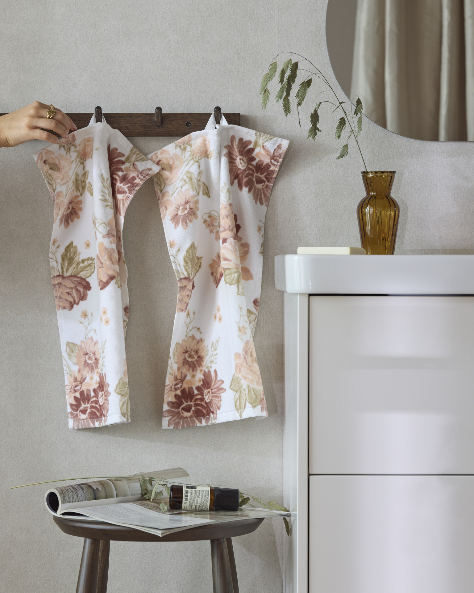 badrumsmiljö med del av kommod synlig, två mönstrade handdukar i ljusa orange och gula toner. 