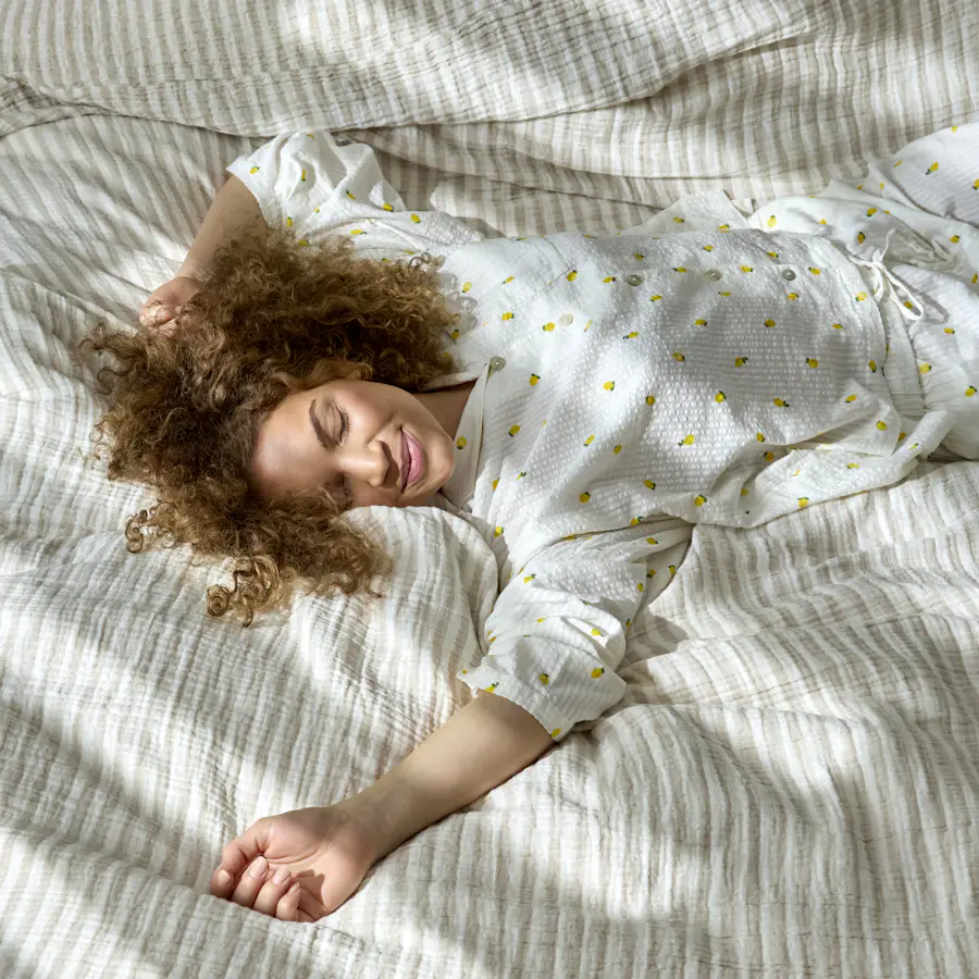En kvinna i pyjamas med citroner på ligger utsträckt på rygg i en säng