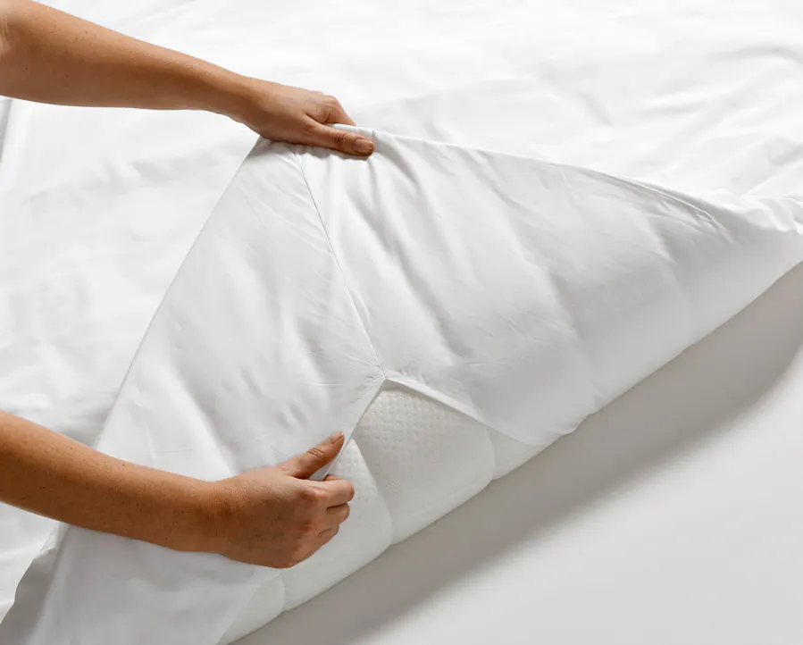 Två händer viker upp en bäddmadrass