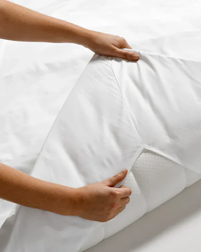 Två händer viker upp en bäddmadrass