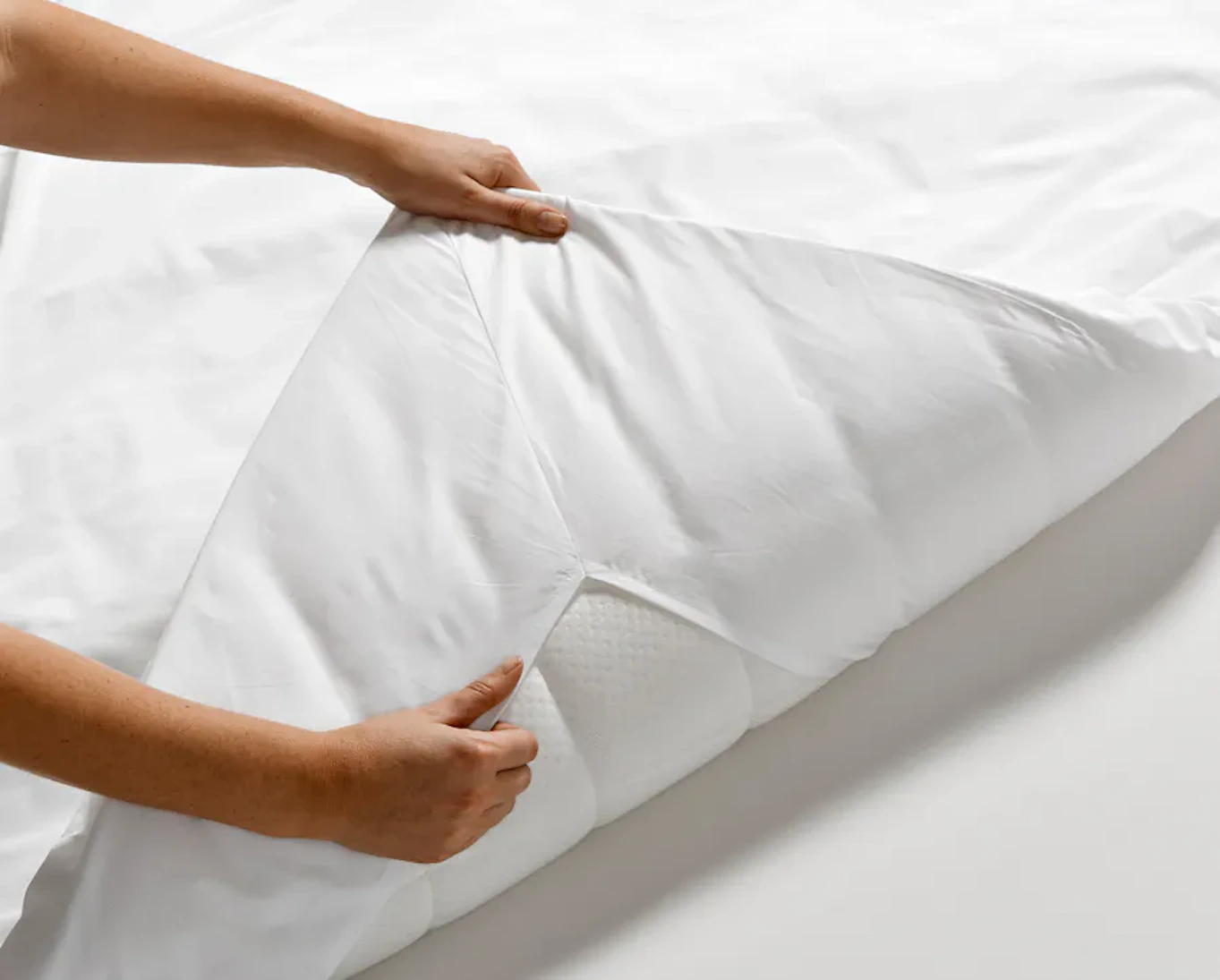 Två händer viker upp en bäddmadrass