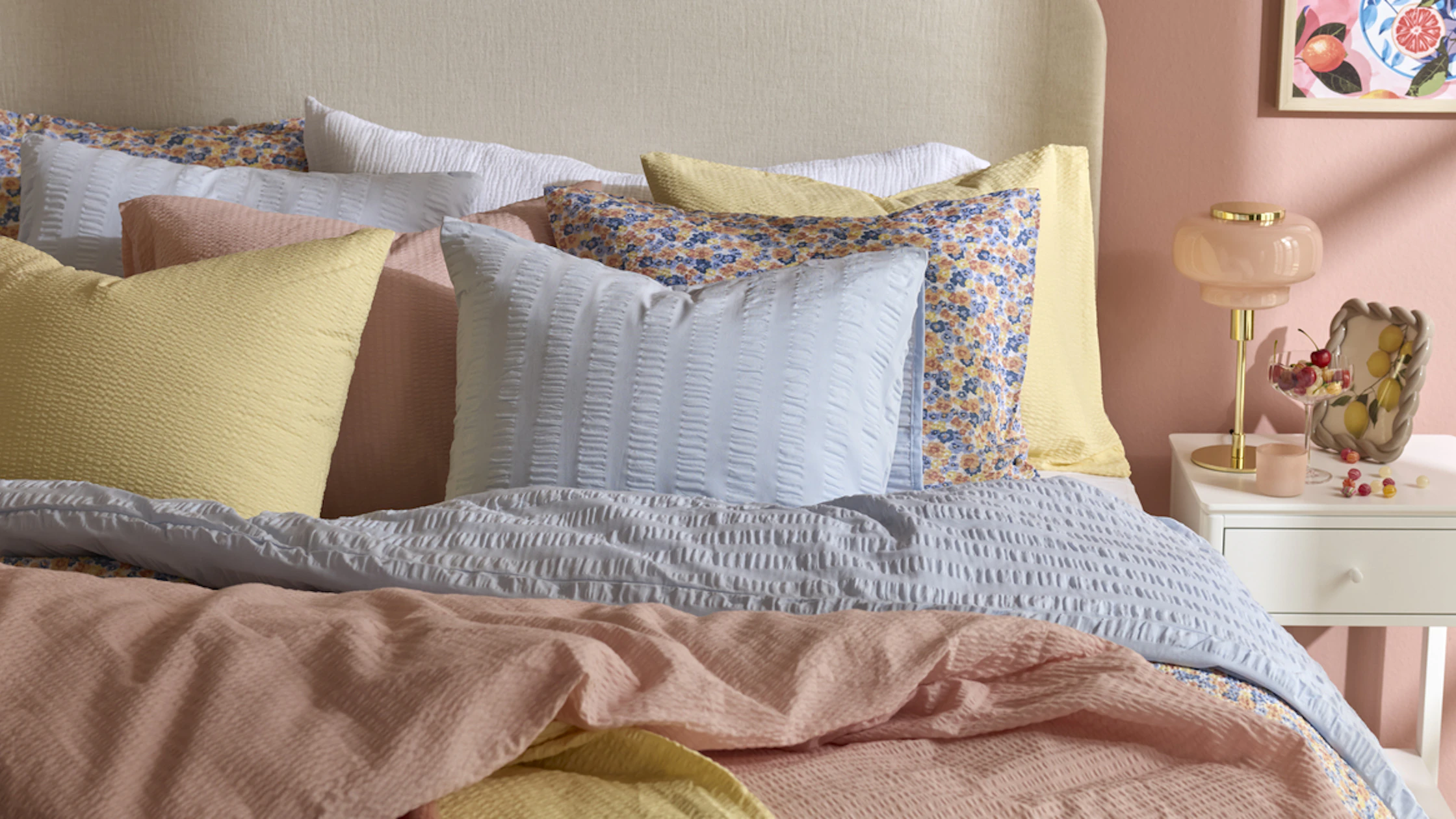 En säng är bäddad med härliga påslakan i rosa, blått och gult