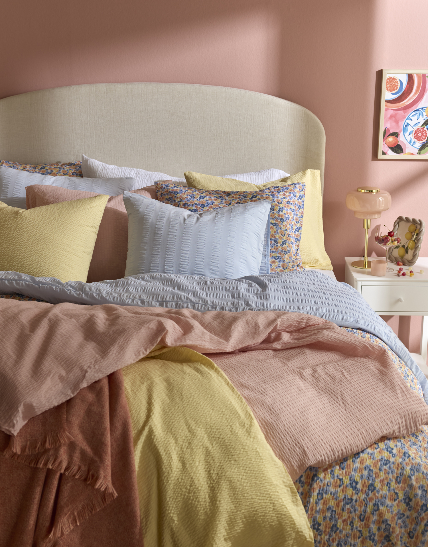 I ett rosa sovrum står en säng bäddad med påslakan i pastellfärger.