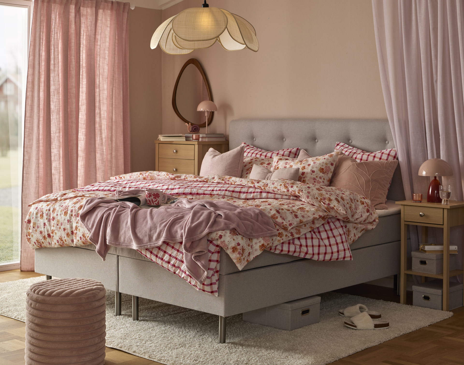 I ett rosa sovrum står Ljusdal kontinentalsäng med blommiga och rutiga sängkläder och kuddar i rosa färger.