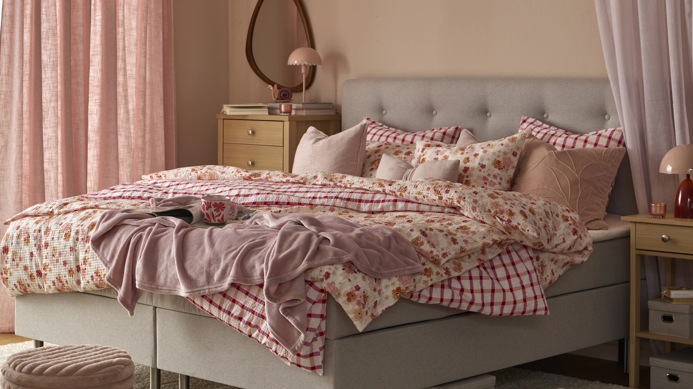 I ett rosa sovrum står Ljusdal kontinentalsäng med blommiga och rutiga sängkläder och kuddar i rosa färger.