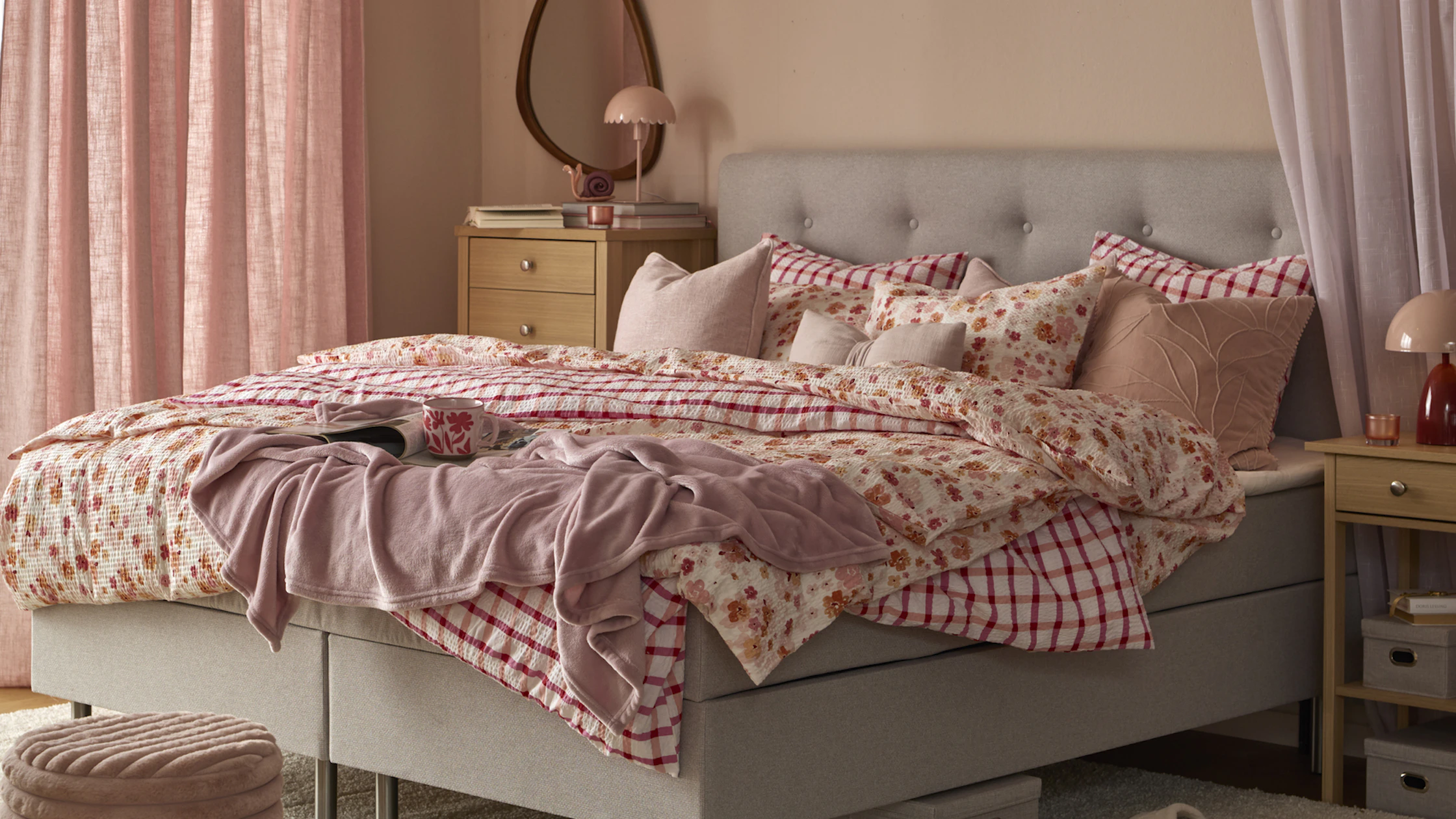 I ett rosa sovrum står Ljusdal kontinentalsäng med blommiga och rutiga sängkläder och kuddar i rosa färger.