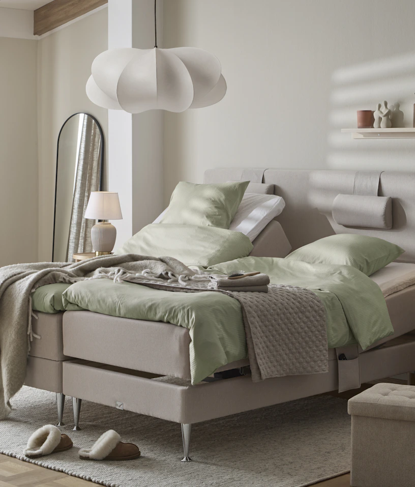 I ett ljust sovrum står två ställbara sängar med gröna sängkläder.