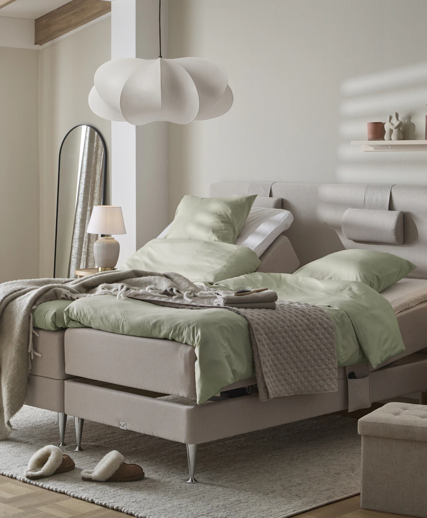 I ett ljust sovrum står två ställbara sängar med gröna sängkläder.