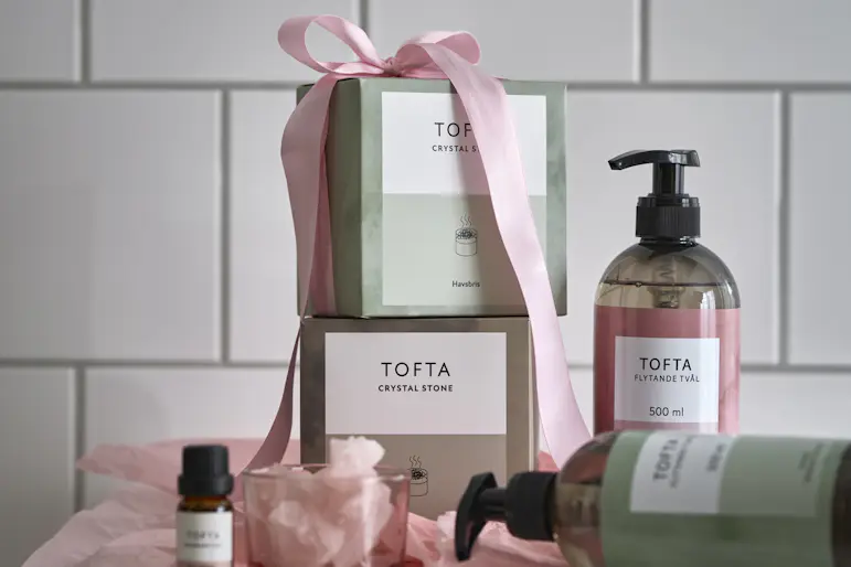 I ett badrum står rosa och gröna förpackningar med handtvål och doftstenar
