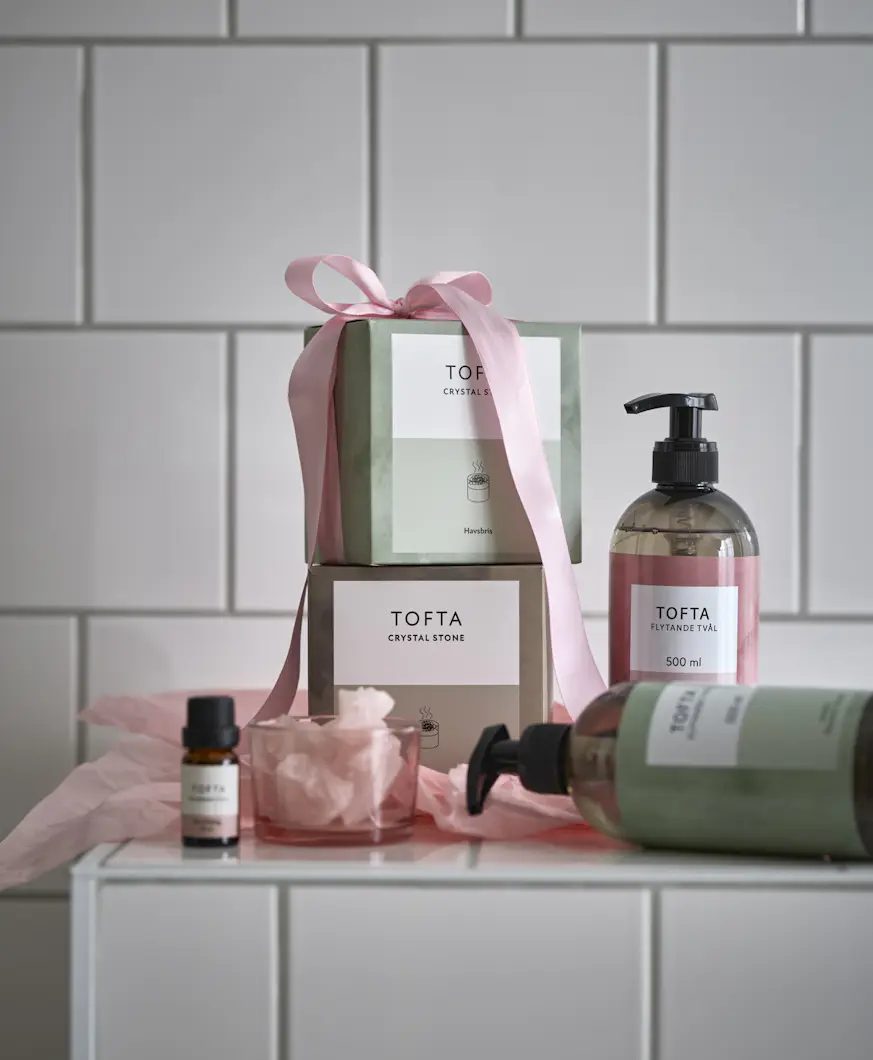 I ett badrum står rosa och gröna förpackningar med handtvål och doftstenar