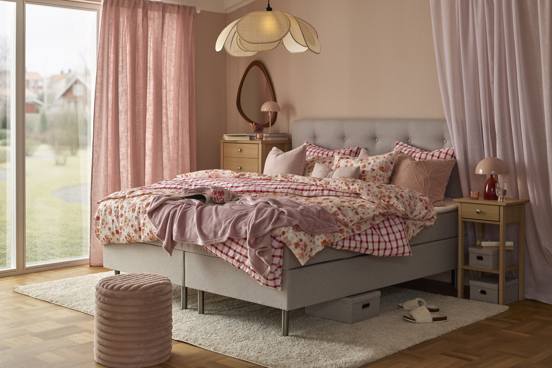 en grå säng bäddad med rosa påslakan i olika mönster står i ett sovrum