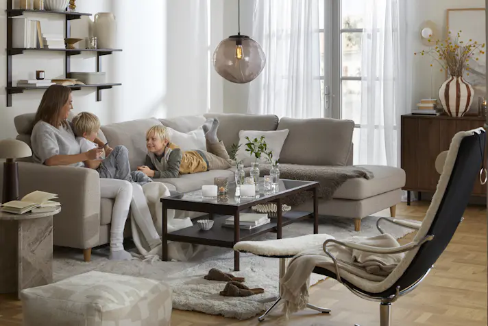 I en beige divansoffa sitter en kvinna och två barn