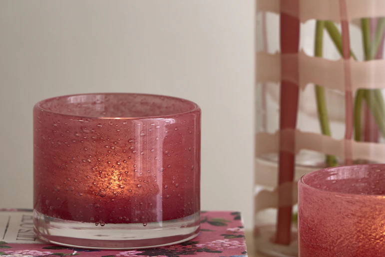 en rosa ljuslykta står på en rosa bok bredvid en vas